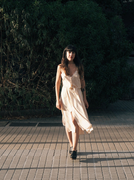 Modelo caminando hacia la cámara con top y falda a conjunto en tejido fluido mostaza y estampado de flores.